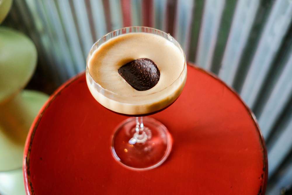 Superbude Hotel Hamburg Altona Bamboole Food Drink 1 Espresso Martini on a stool in front of the counter of the Bamboole restaurant.