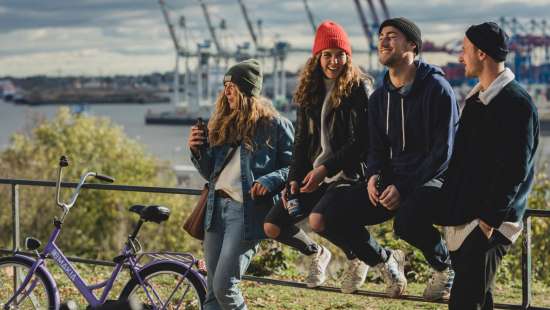 Gruppe am Geländer mit Rädern und Hafenkulisse.