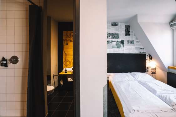 View of the hotel bed and into the open bathroom door.