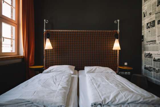 Hotel bed with white sheets and atmospheric lighting.