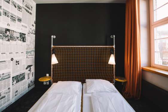 Made hotel bed against a dark wall with cozy lighting.