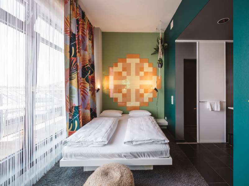 Doppelbude L mit Balkon Wandkunst und offenem Bad neben dem Bett.