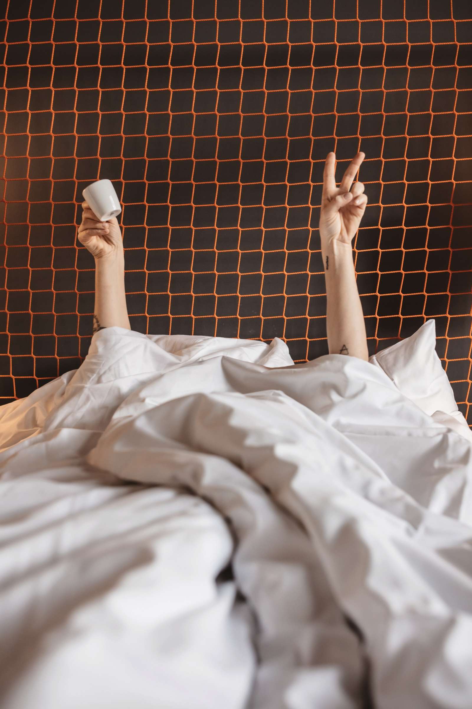 Arms protrude from a white bedsheet, a relaxed awakening.